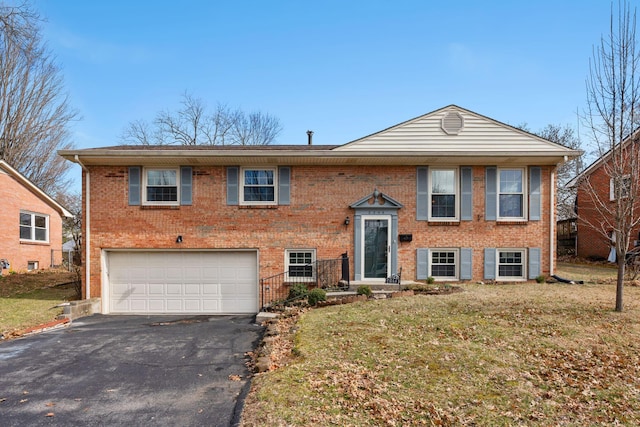 bi-level home with driveway, an attached garage, a front lawn, and brick siding