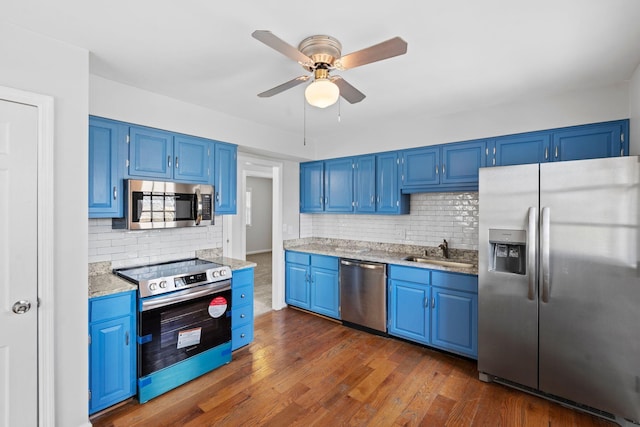 kitchen featuring dark wood-style flooring, a sink, appliances with stainless steel finishes, blue cabinetry, and tasteful backsplash