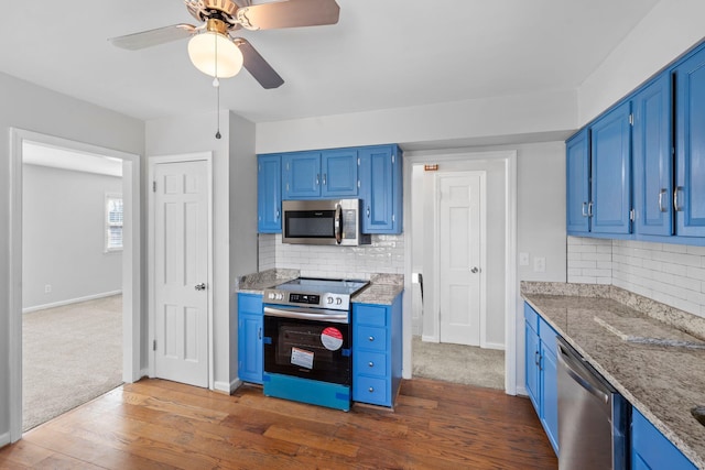 kitchen featuring appliances with stainless steel finishes, dark wood-style flooring, blue cabinets, and backsplash