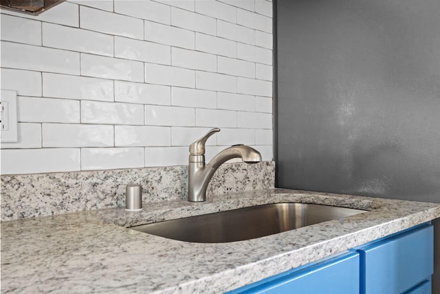 details featuring blue cabinetry, a sink, and decorative backsplash