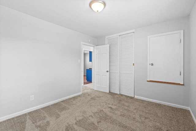 unfurnished bedroom with carpet floors, baseboards, and a closet