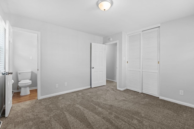 unfurnished bedroom featuring carpet, a closet, baseboards, and ensuite bathroom