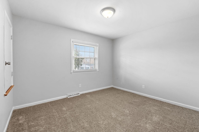 carpeted spare room featuring visible vents and baseboards