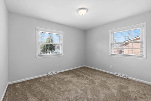 spare room with visible vents, plenty of natural light, and carpet flooring