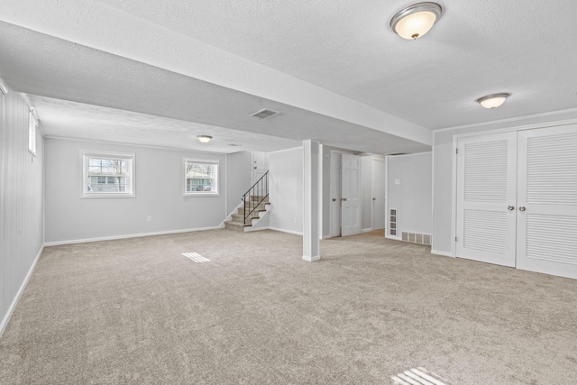 basement with carpet, visible vents, stairway, and baseboards