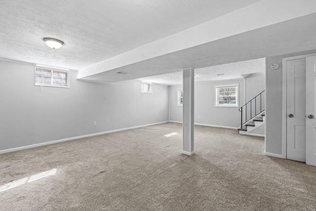 basement featuring carpet flooring, a textured ceiling, baseboards, and stairs