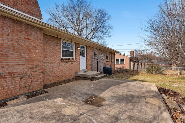 exterior space featuring a patio, brick siding, and fence