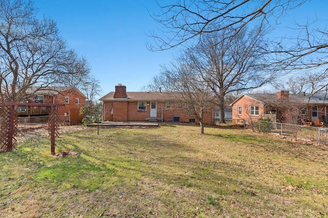 back of property featuring a patio, a chimney, fence, a yard, and brick siding