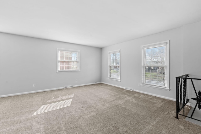 carpeted empty room with visible vents and baseboards