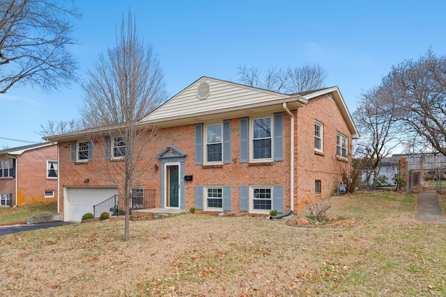 split foyer home with aphalt driveway, an attached garage, fence, a front lawn, and brick siding