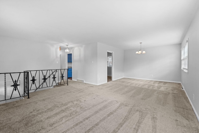 empty room featuring baseboards, carpet floors, visible vents, and an inviting chandelier