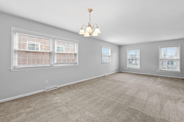 carpeted empty room featuring baseboards, visible vents, and a chandelier