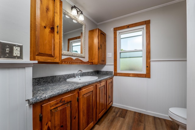 bathroom with toilet, plenty of natural light, wood finished floors, and vanity