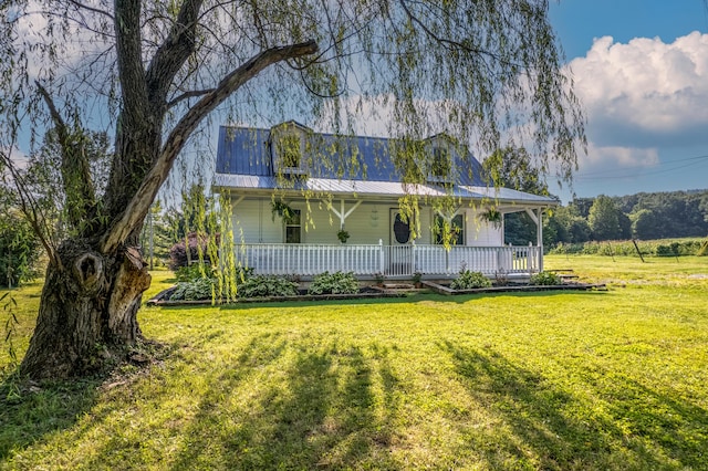 view of front of property featuring covered porch, metal roof, and a front yard