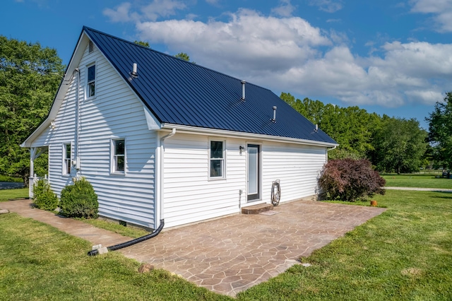 rear view of property featuring metal roof, a patio, and a yard