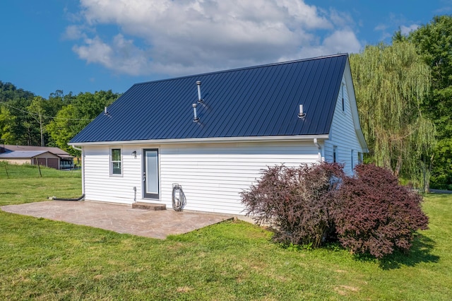 rear view of house featuring metal roof, a patio area, and a yard