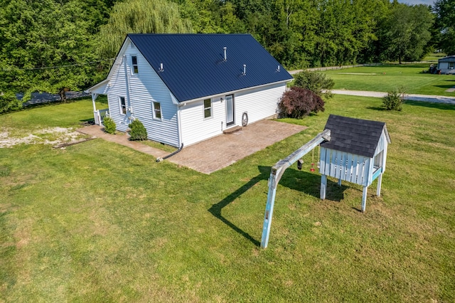 rear view of property featuring a yard, metal roof, and a patio