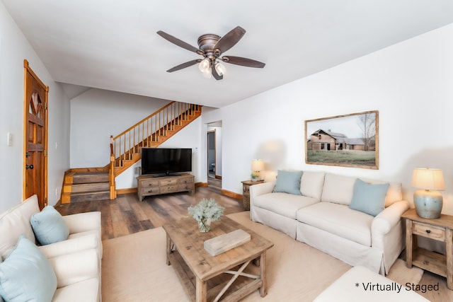 living room with baseboards, ceiling fan, stairway, and wood finished floors