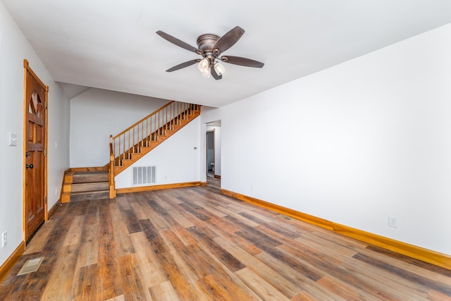 spare room with stairway, wood finished floors, visible vents, and baseboards