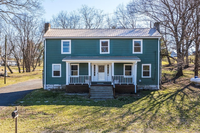 view of front of house with metal roof, a chimney, a front lawn, and a porch