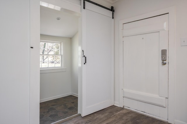 entryway with a barn door, baseboards, and dark wood finished floors