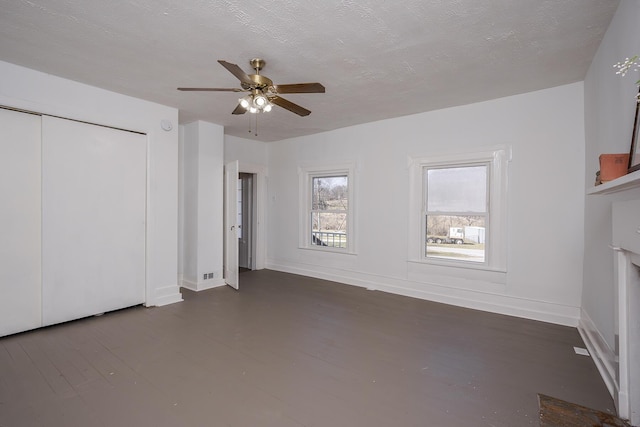 unfurnished bedroom featuring ceiling fan, a fireplace, baseboards, and a textured ceiling