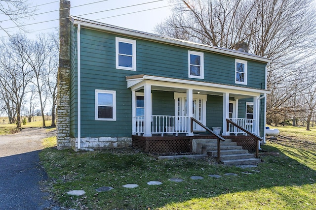 view of front of house with covered porch, driveway, and a chimney