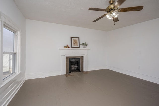 unfurnished living room with wood finished floors, a fireplace with flush hearth, a ceiling fan, and baseboards