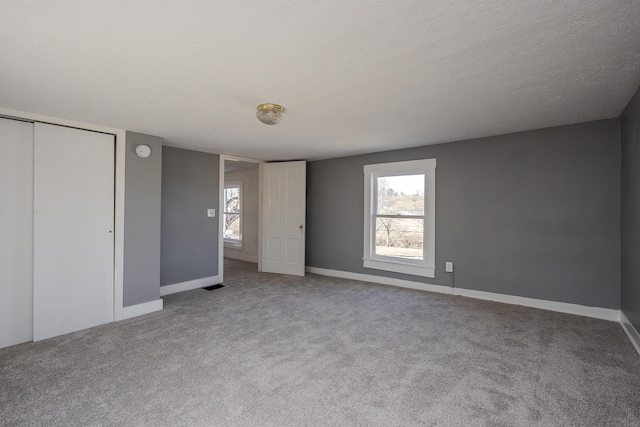 unfurnished bedroom featuring carpet, a closet, baseboards, and a textured ceiling