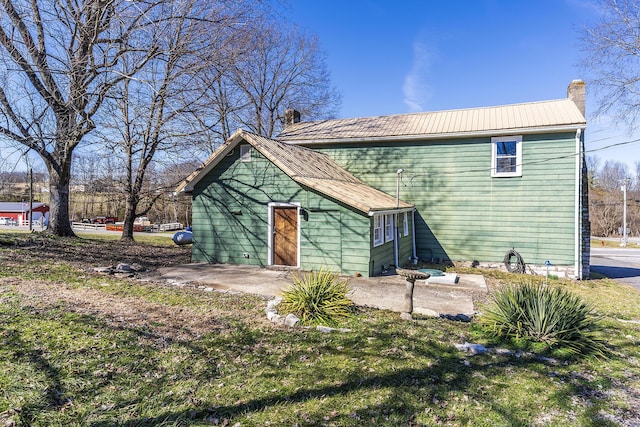 rear view of house with a chimney, metal roof, and a patio