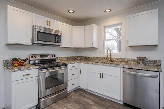 kitchen with stainless steel appliances, a sink, white cabinets, light stone countertops, and dark wood-style floors