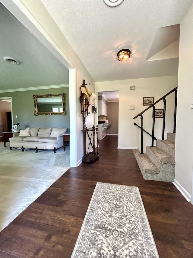 foyer with stairway, visible vents, wood finished floors, and ornamental molding