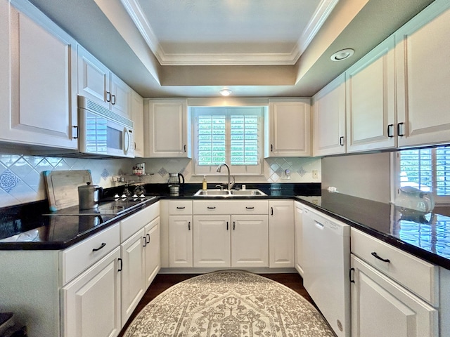 kitchen featuring a tray ceiling, white appliances, a sink, and white cabinetry