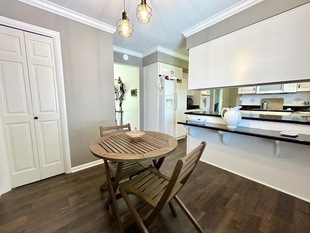 kitchen with crown molding, dark countertops, white appliances, and dark wood finished floors