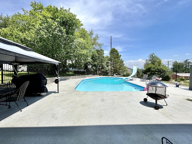 view of swimming pool with a patio, a water slide, fence, and a fenced in pool