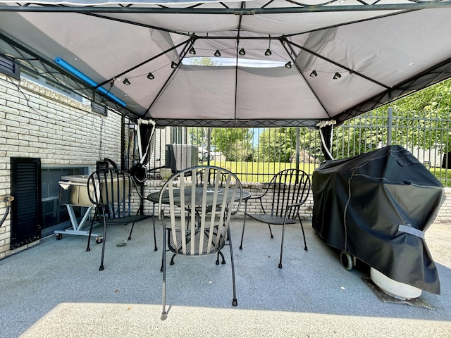 view of patio with fence, outdoor dining area, and a gazebo