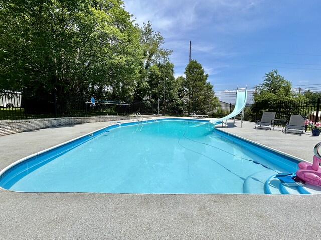 view of swimming pool with a water slide, a patio area, fence, and a fenced in pool