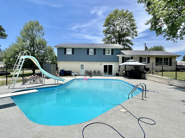 view of pool featuring a patio area, a fenced in pool, fence, and a water slide