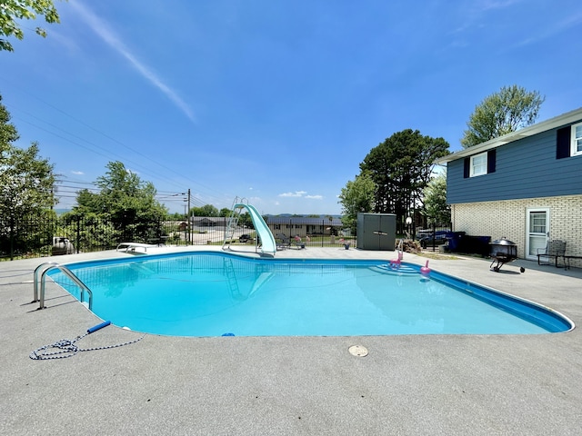 view of pool featuring a water slide, a patio area, fence, and a fenced in pool