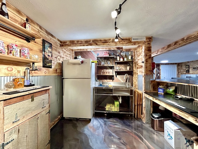 interior space featuring visible vents, freestanding refrigerator, wood walls, concrete floors, and open shelves