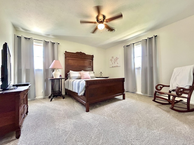 bedroom featuring a ceiling fan, light carpet, and a textured ceiling