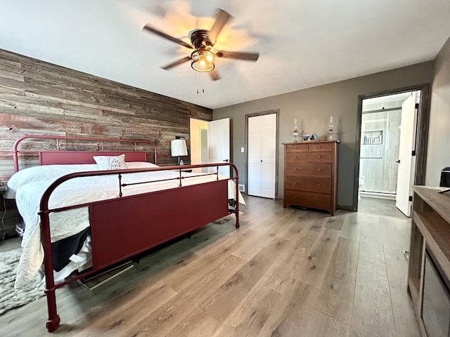 bedroom featuring ceiling fan, wood walls, and wood finished floors