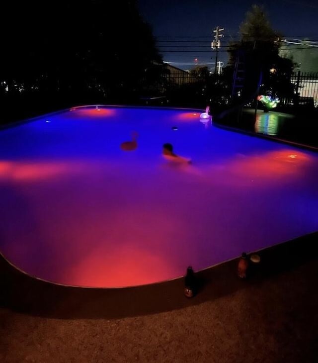 view of pool at twilight