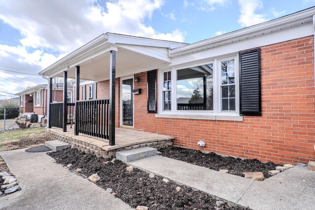 property entrance with covered porch and brick siding