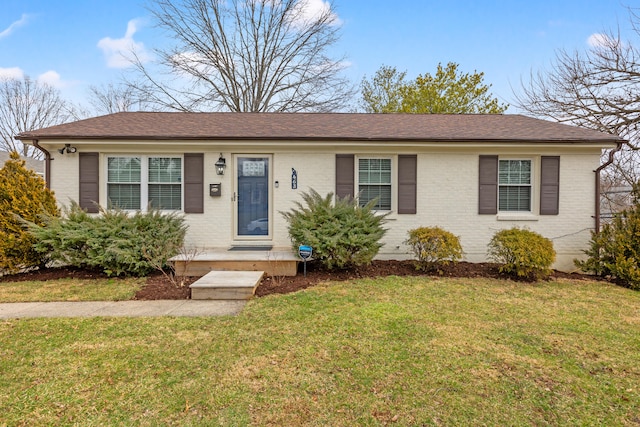 single story home with roof with shingles, a front yard, and brick siding