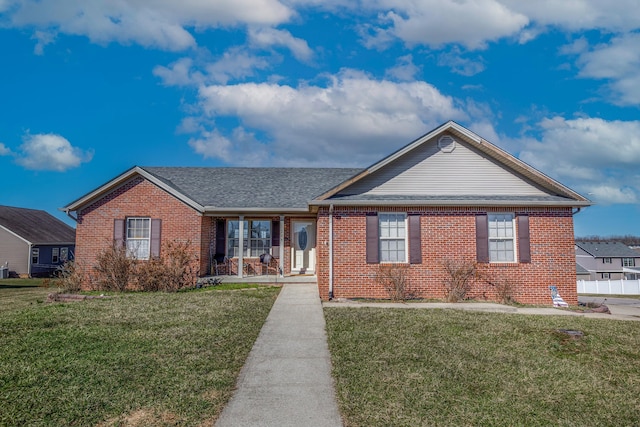 ranch-style home with a shingled roof, a front lawn, and brick siding