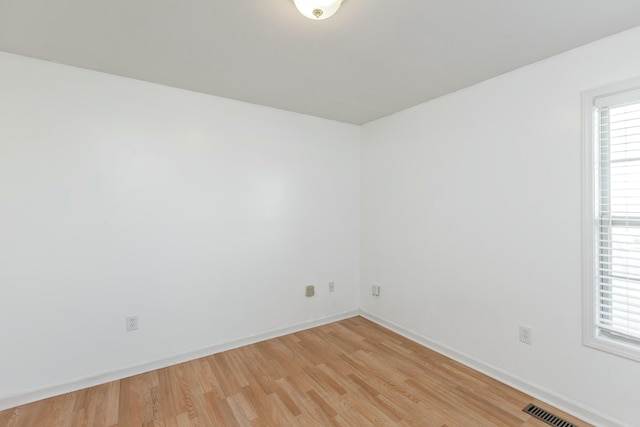 unfurnished room with light wood finished floors, visible vents, and baseboards