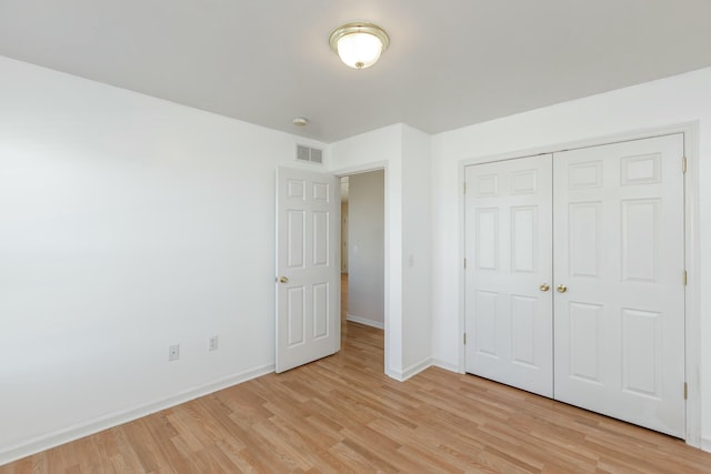 unfurnished bedroom featuring light wood-style flooring, a closet, visible vents, and baseboards