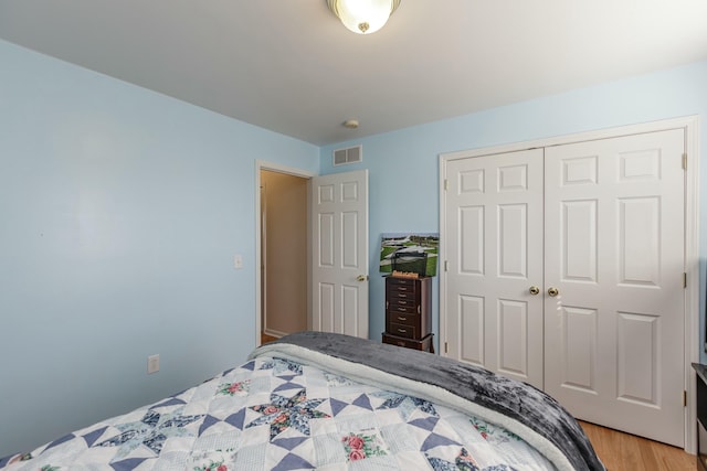 bedroom with light wood-style flooring, visible vents, and a closet