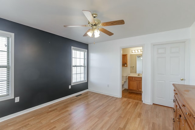 unfurnished bedroom with ceiling fan, ensuite bathroom, visible vents, baseboards, and light wood finished floors